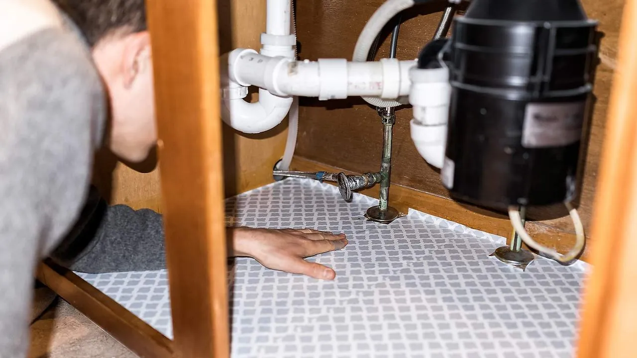 Checking for a leak under a kitchen sink with a garbage disposal