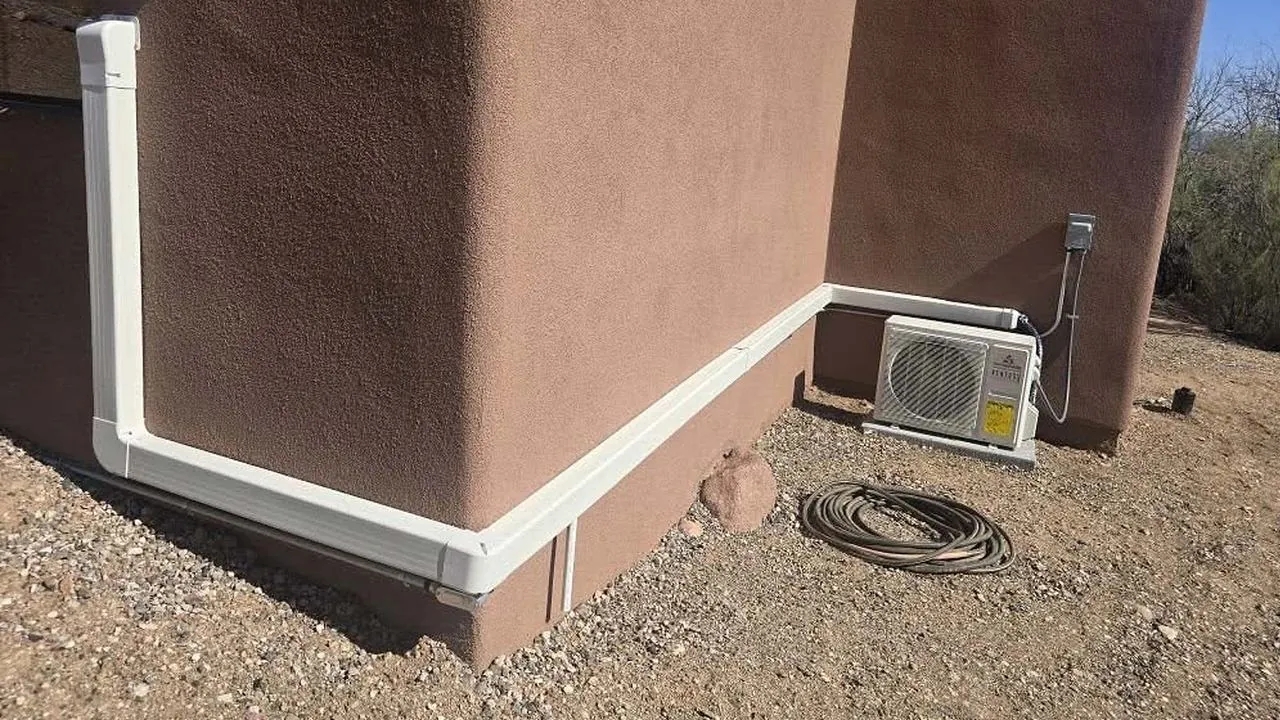 Mini-split outdoor unit with a line set cover along a stucco home