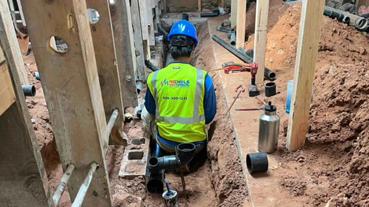 Nichols plumber working in a rough-in trench at a construction site