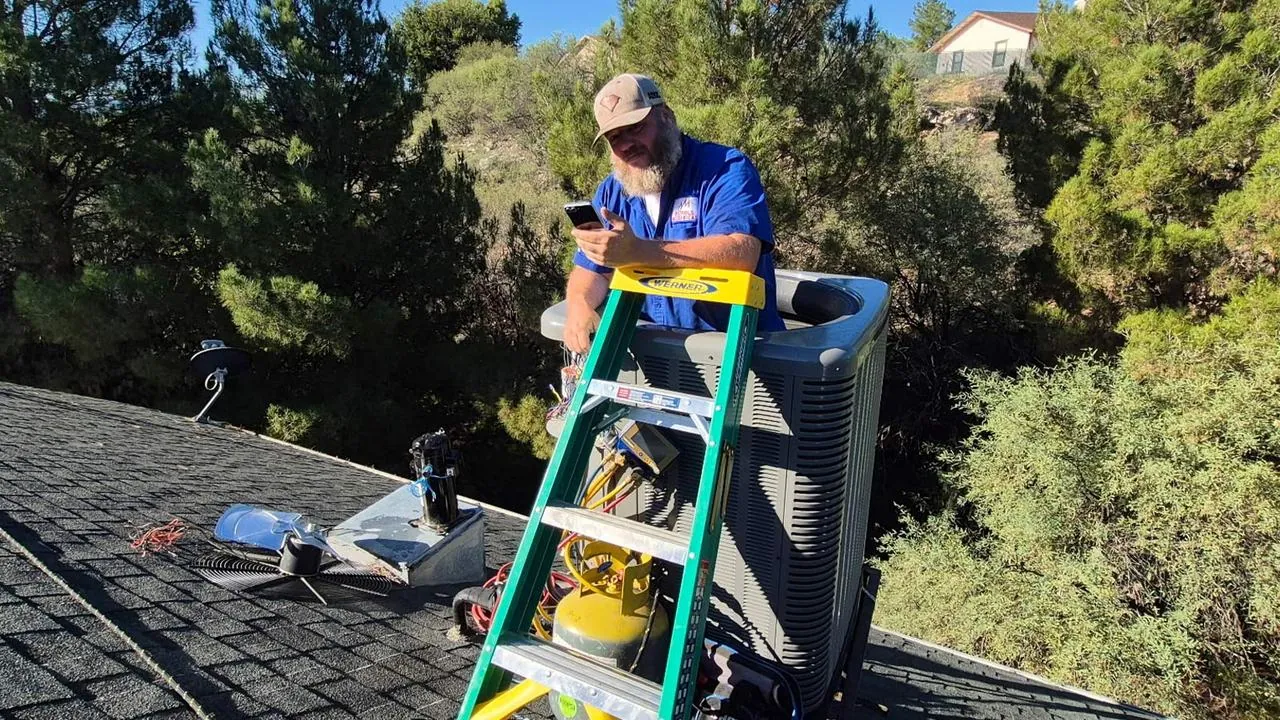 Nichols technician on a ladder maintaining a rooftop AC unit
