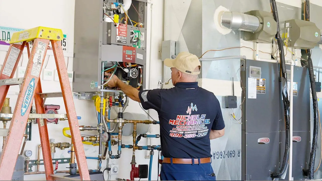 Nichols technician repairing water heating equipment in a mechanical room