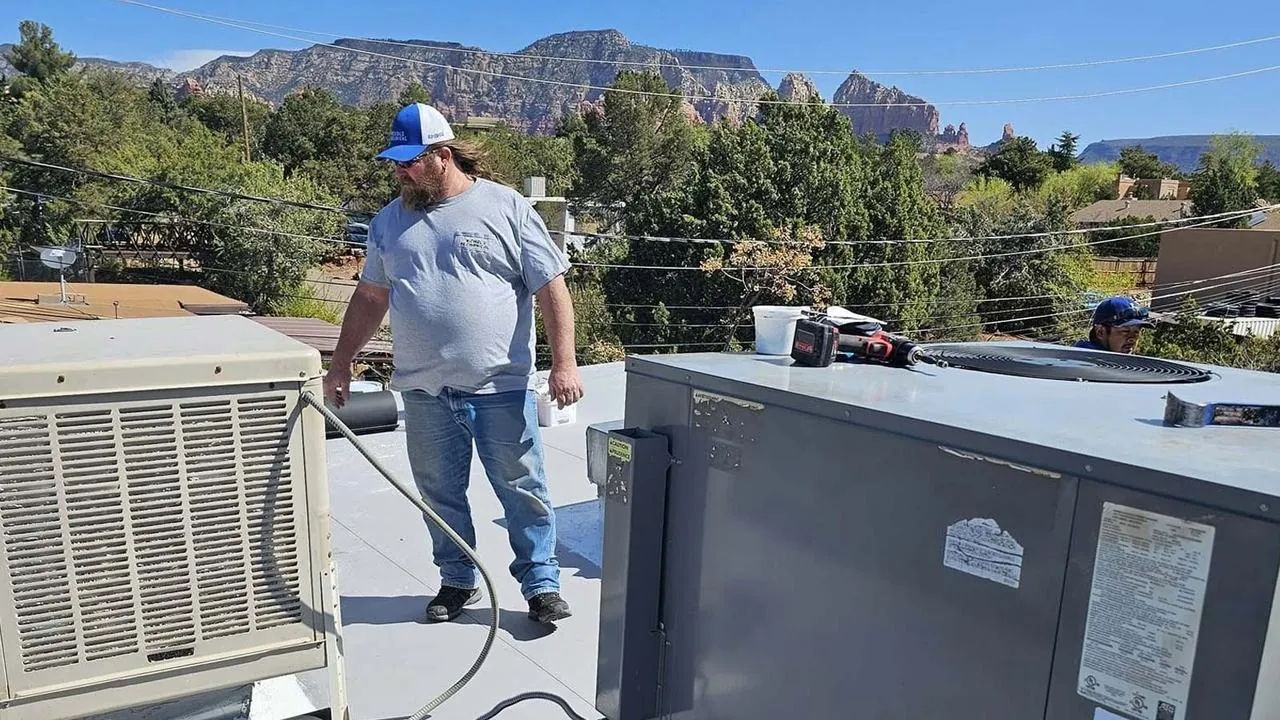 Technician working on rooftop HVAC units with Sedona red rocks in the background