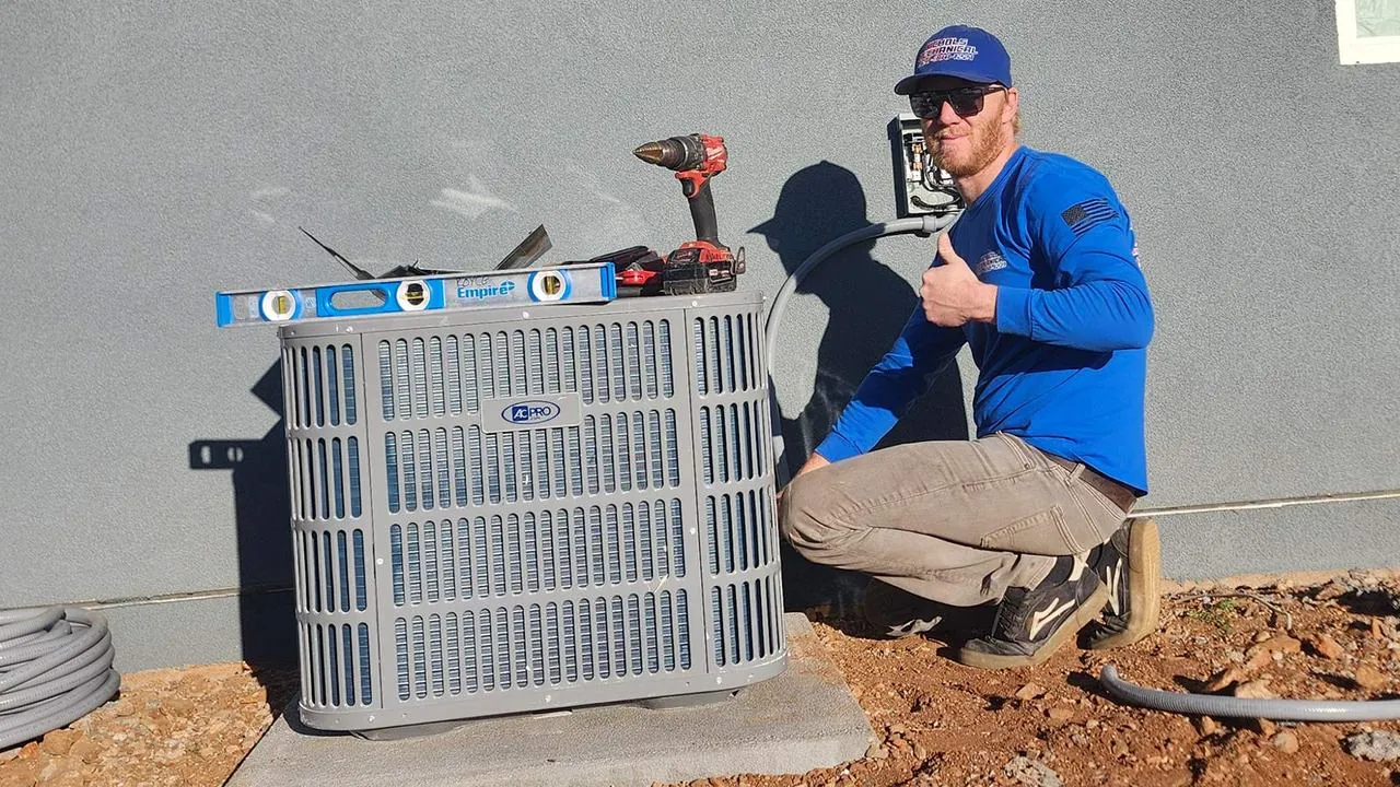 Technician giving a thumbs up beside a newly installed AC condenser