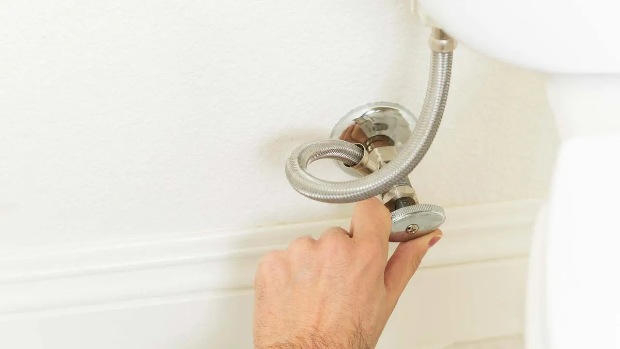 Hand turning a toilet water supply valve