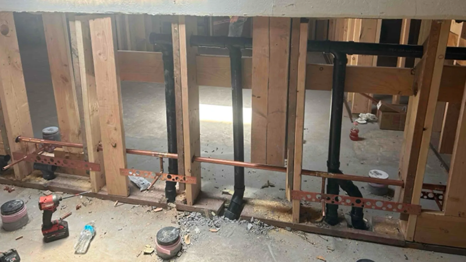 Commercial bathroom plumbing rough-in with drain and supply lines in open framing