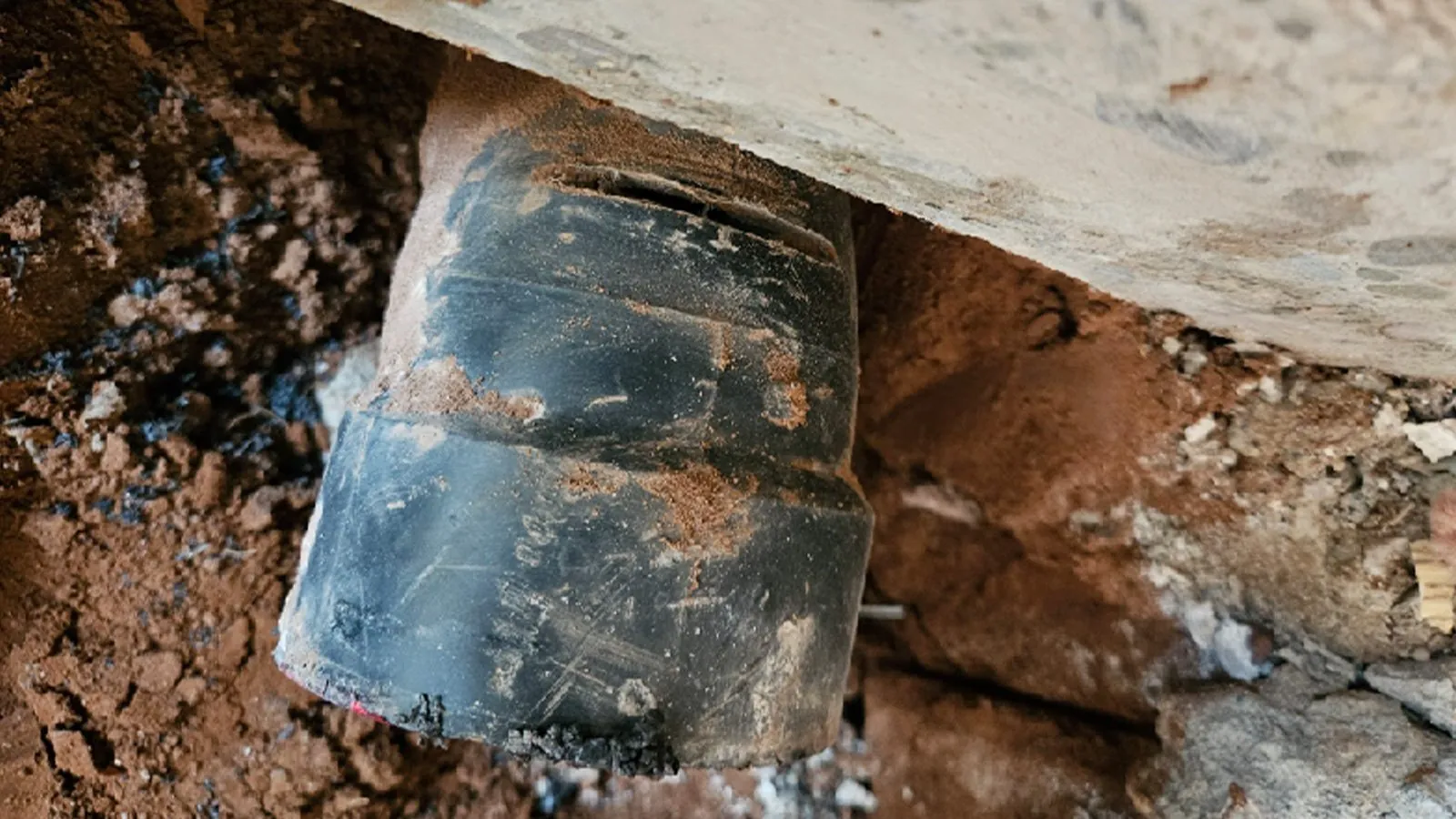Cracked ABS drain pipe exposed under a slab