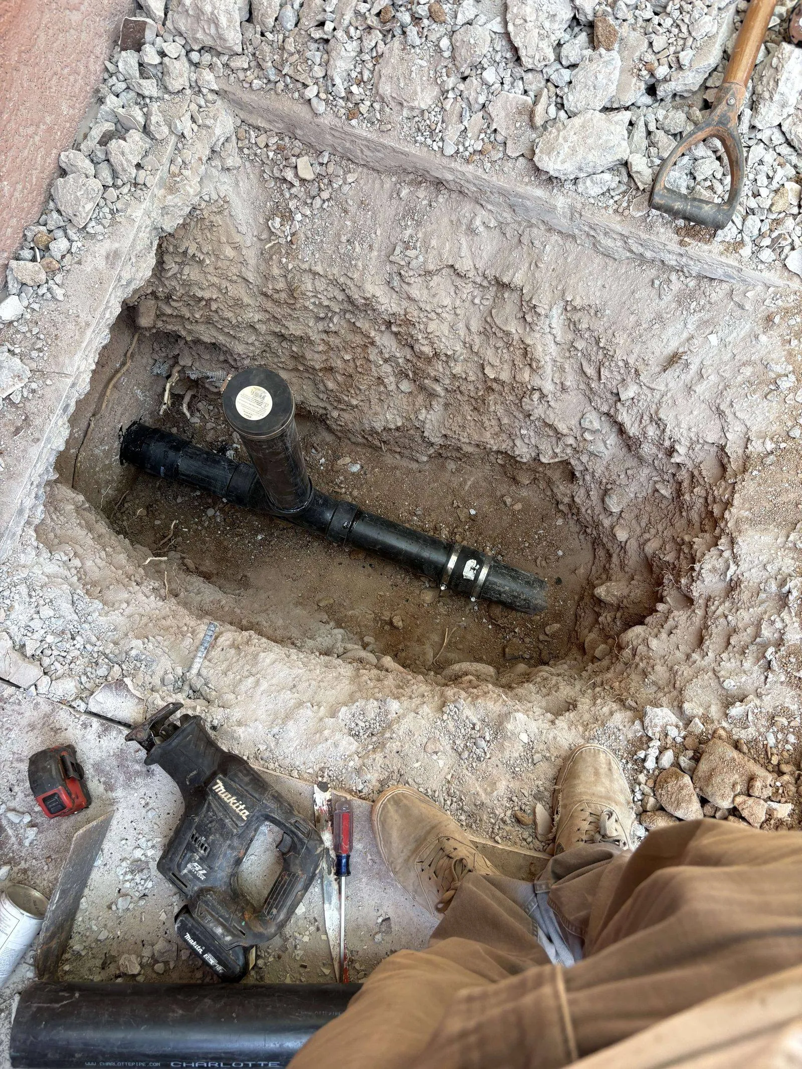New pipe section installed in a hole under a concrete slab