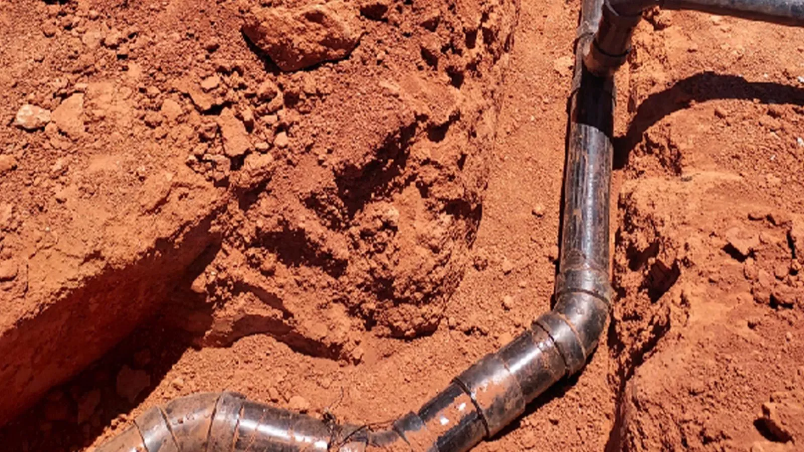 New sewer line laid in a red dirt trench