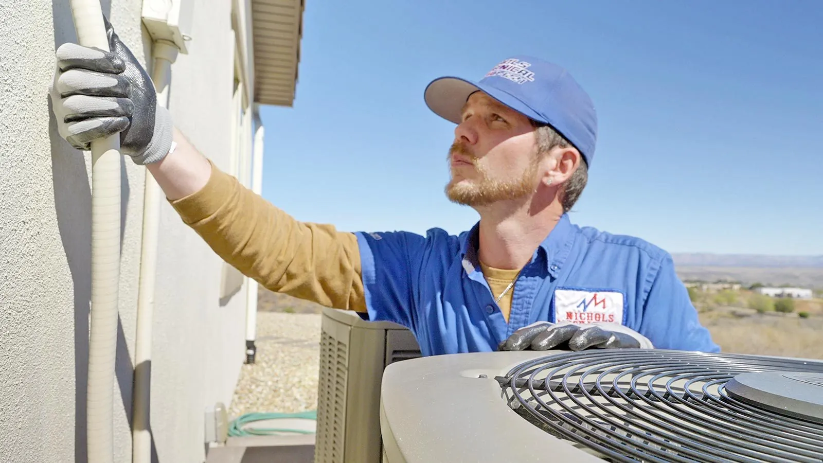 Nichols technician inspecting an outdoor AC condenser