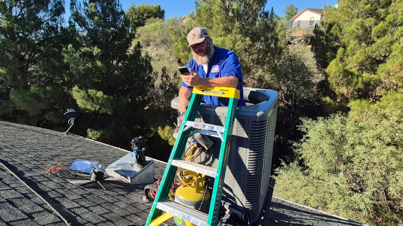 Nichols technician on a ladder maintaining a rooftop AC unit