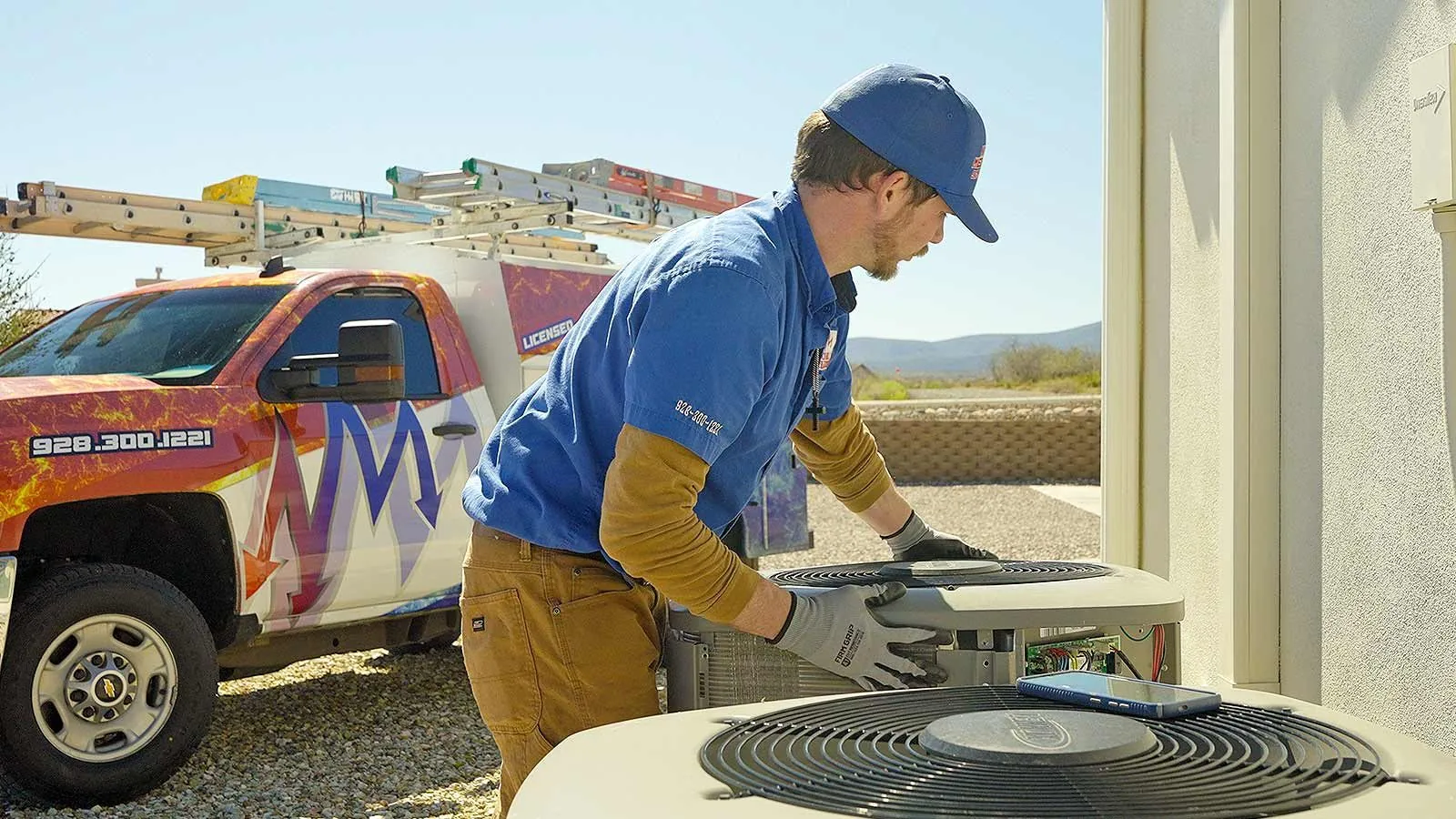 Nichols technician servicing an AC condenser fan next to his service truck
