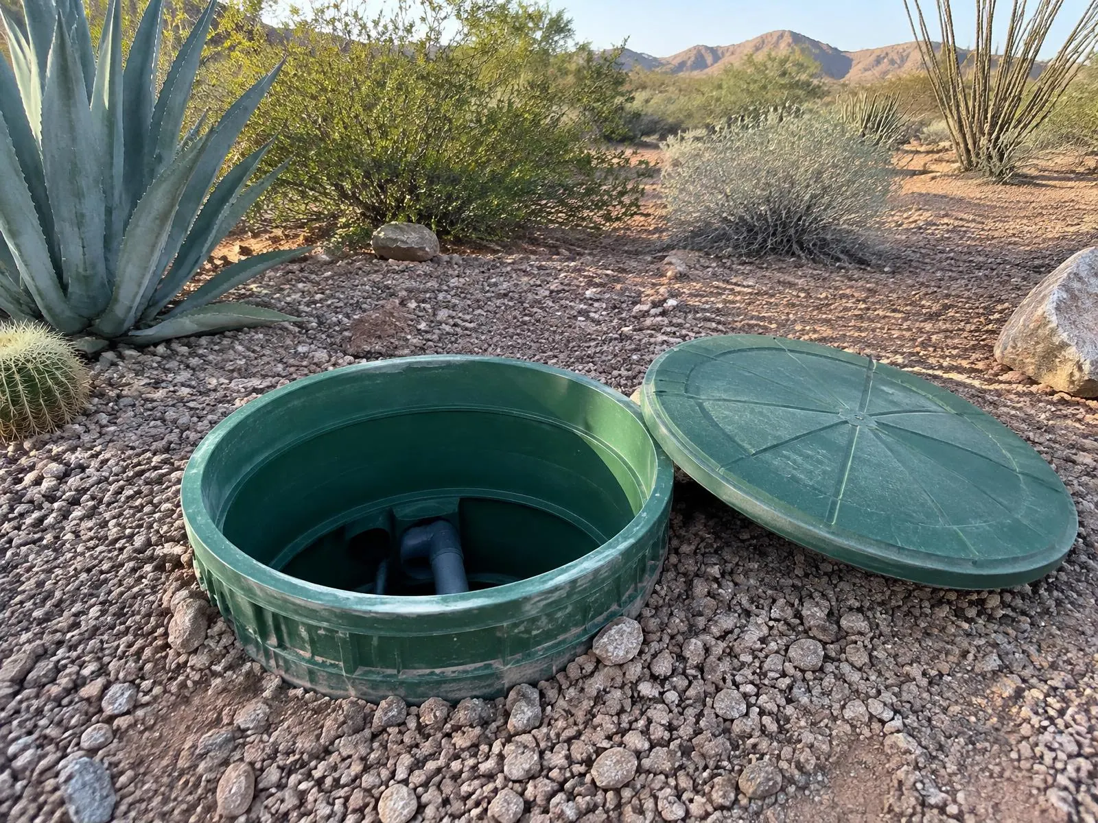 Open septic tank riser and lid in an Arizona yard
