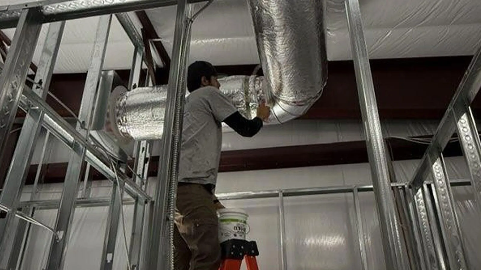 Technician installing ductwork in a commercial building
