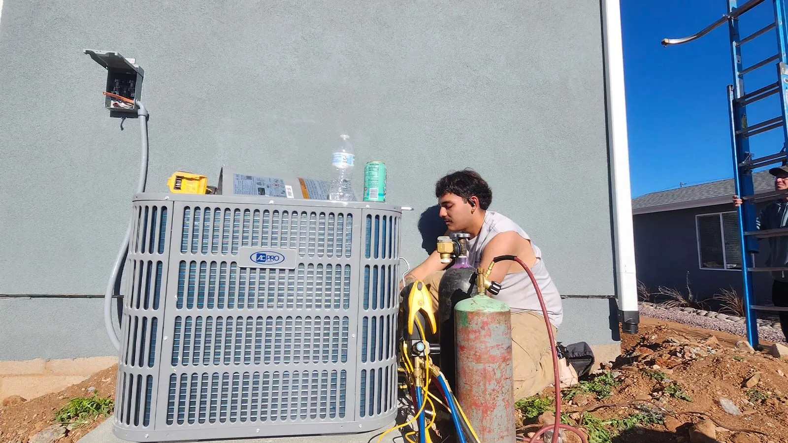 Technician installing a new AC condenser beside a home