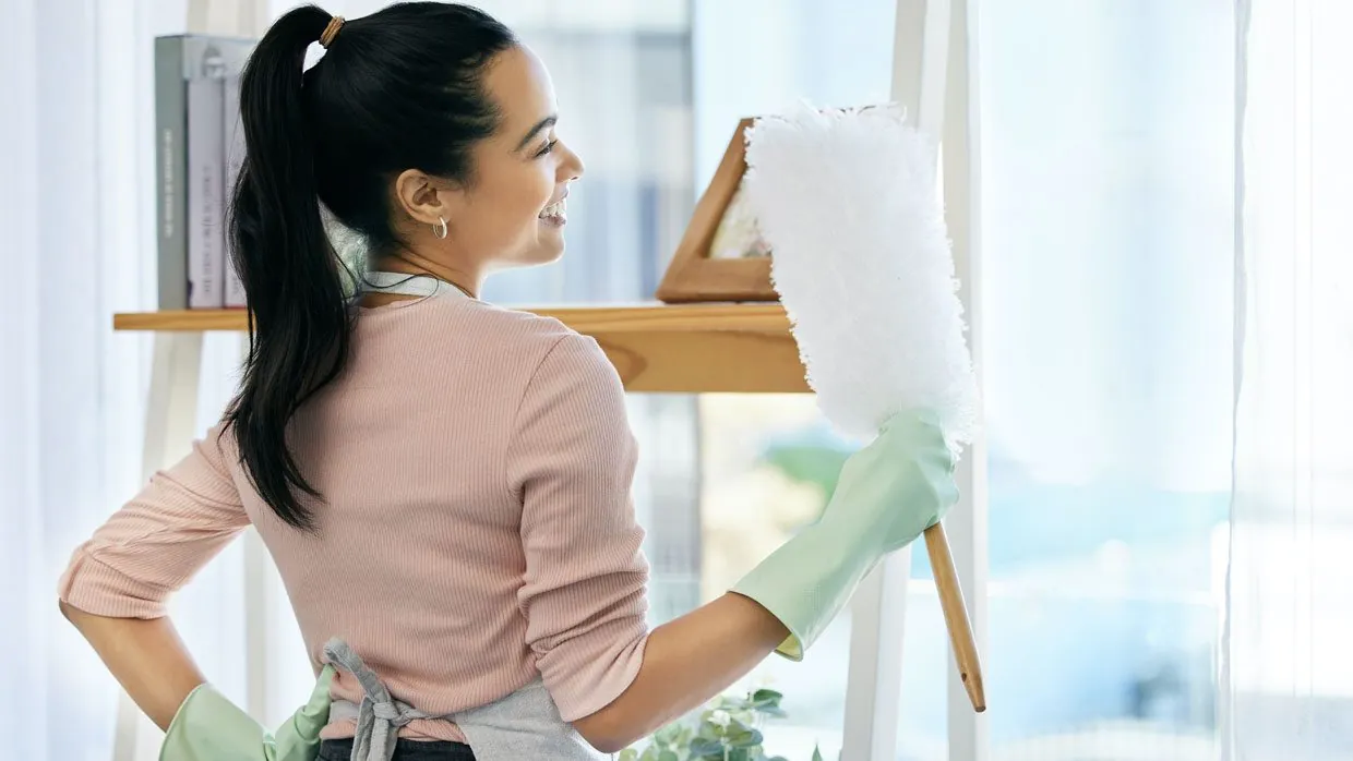 Woman dusting shelves at home